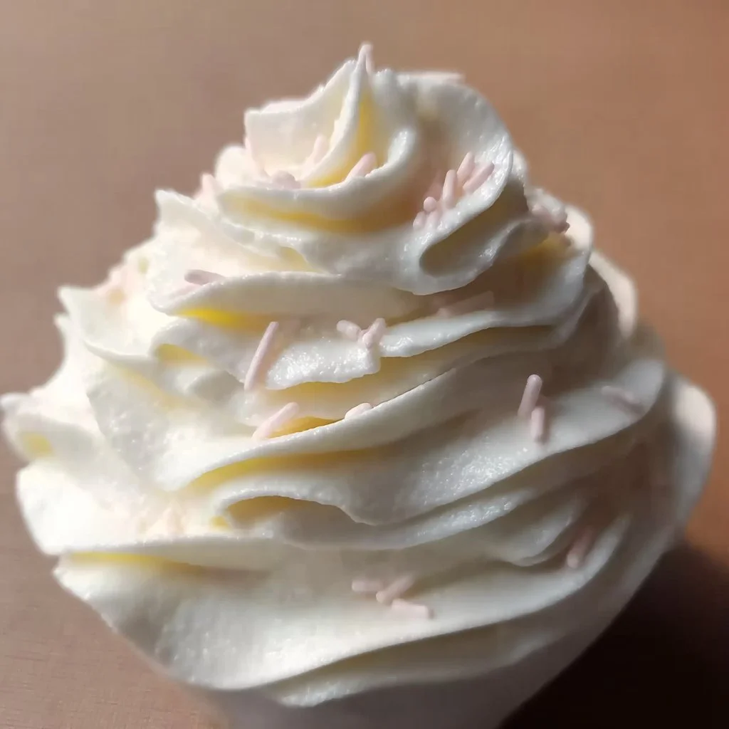 Bowl of stabilized whipped cream topped with berries on a dessert plate.