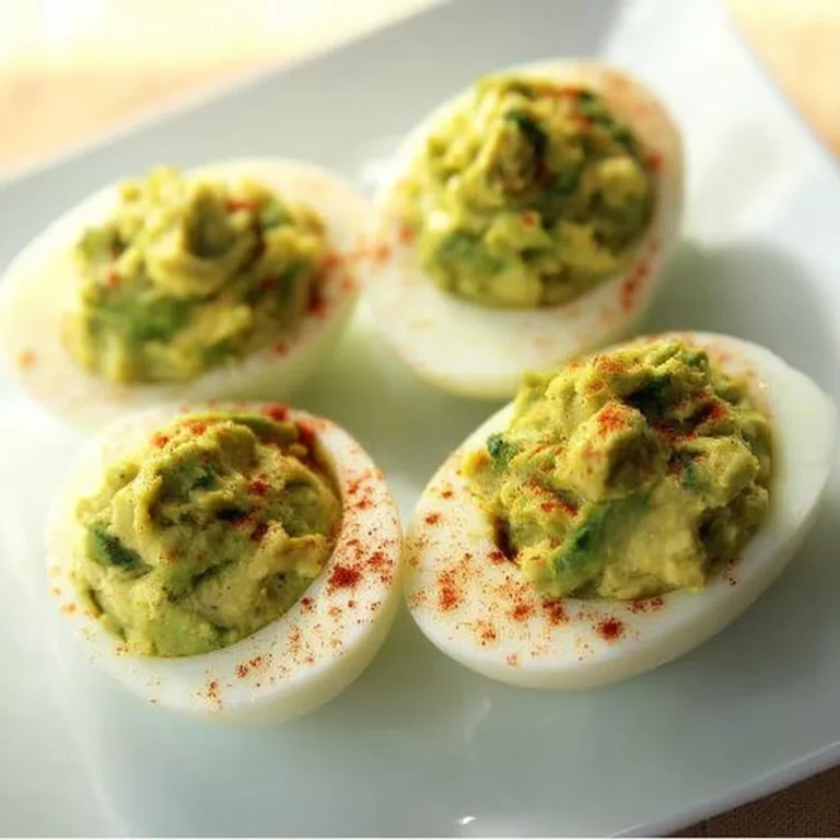 A plate of Avocado Deviled Eggs garnished with herbs and spices.